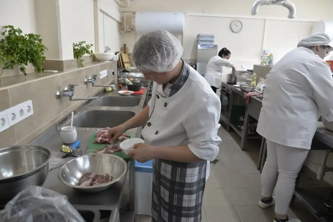 Шкільний харчоблок, кухар готує їжу