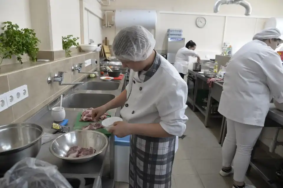 Шкільний харчоблок, кухар готує їжу