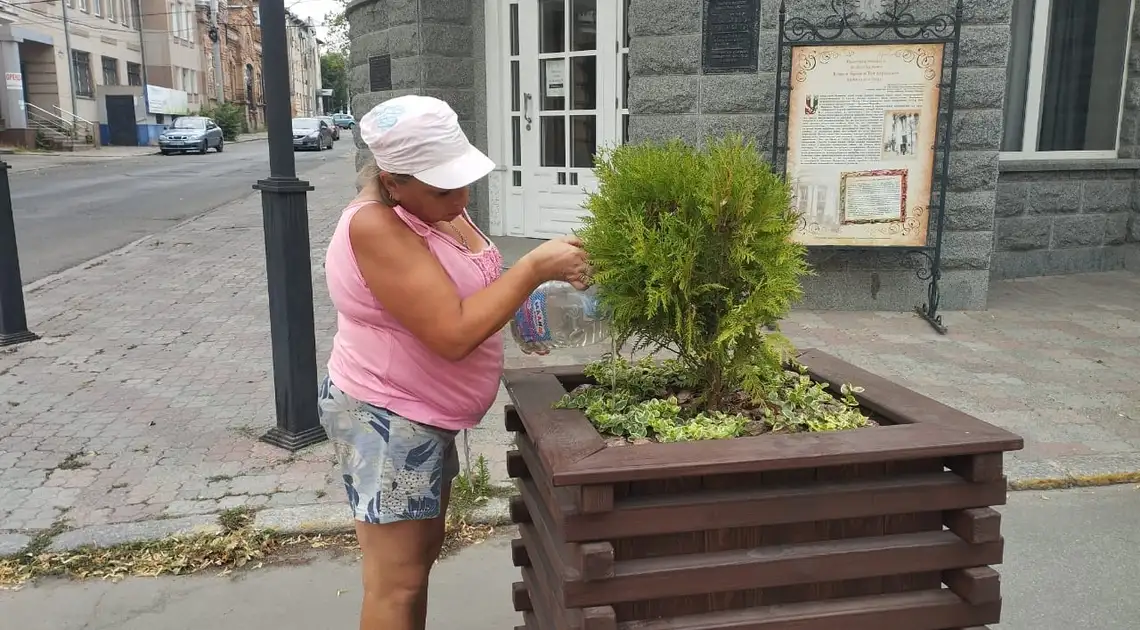 жінка поливає дерево