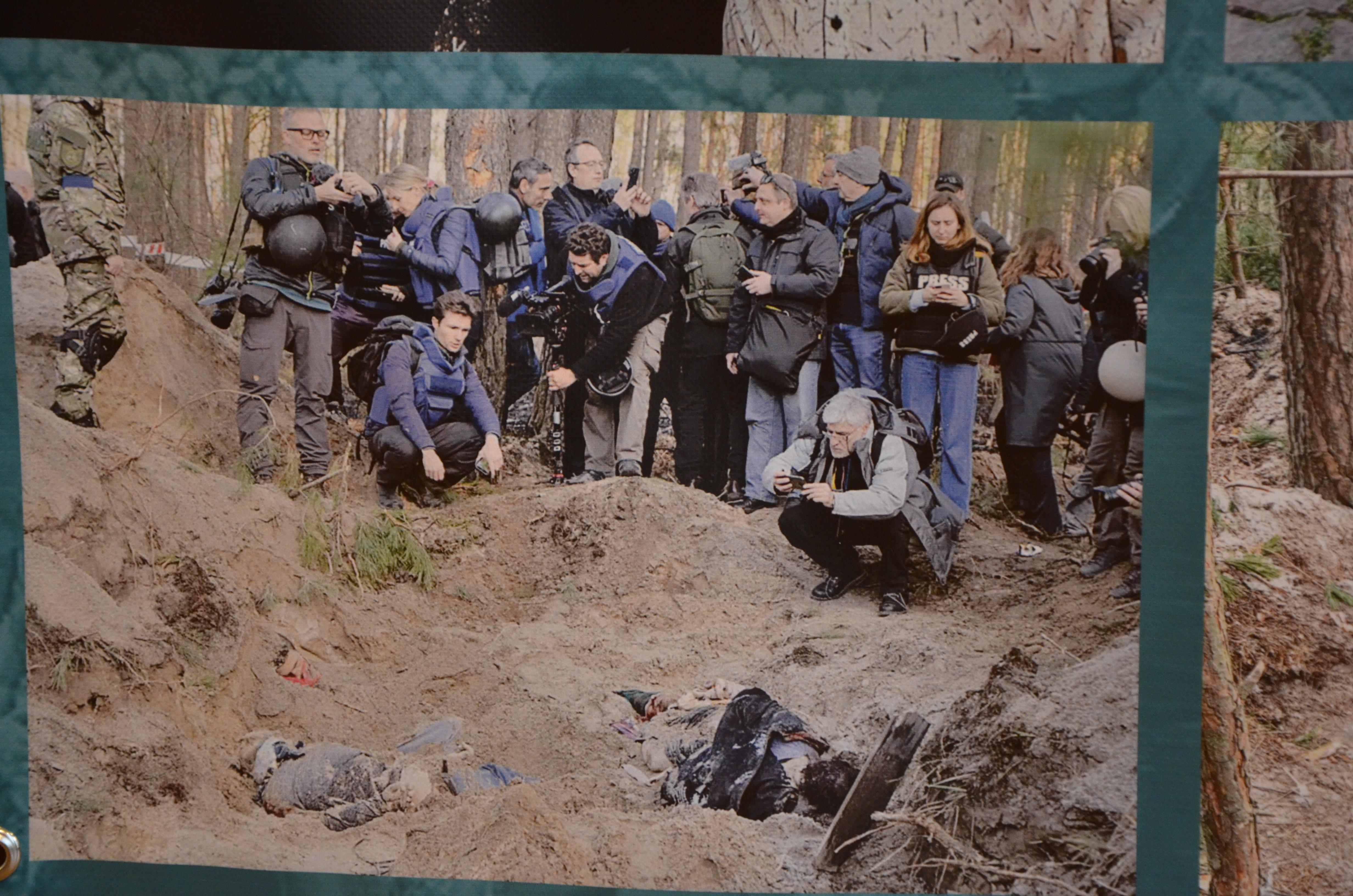 Фото на стенді, на якому зображена ексгумація тіл з братської могили біля села Мотижин
