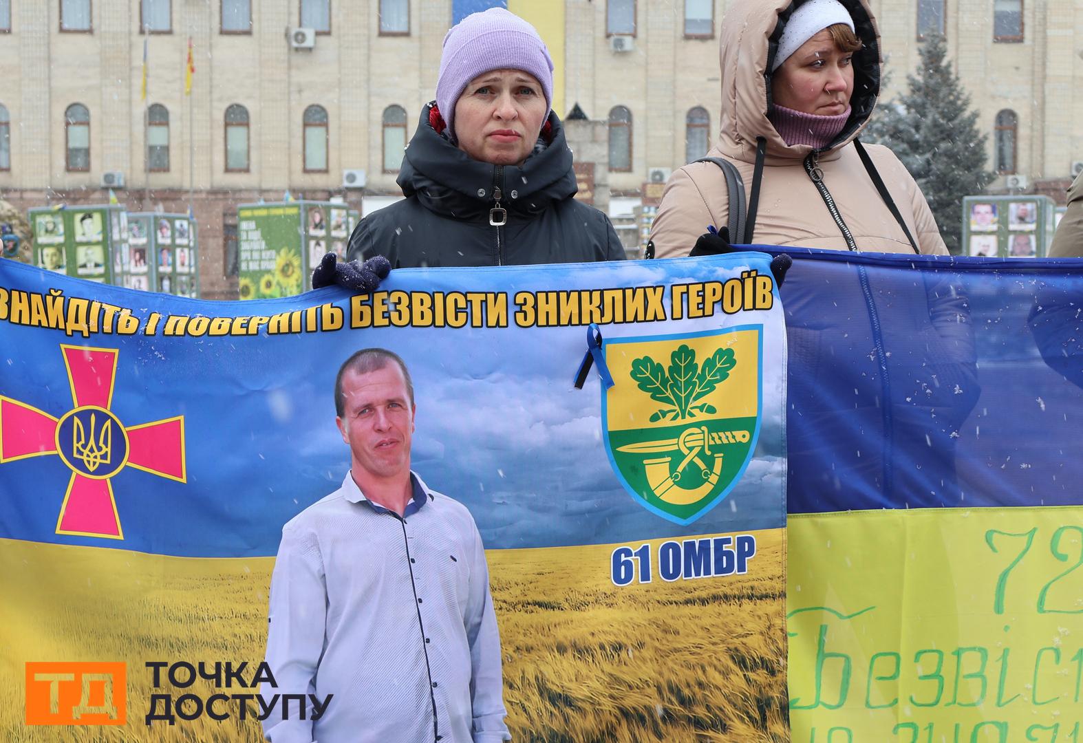 Жінка тримає плакат з портретом свого чоловіка