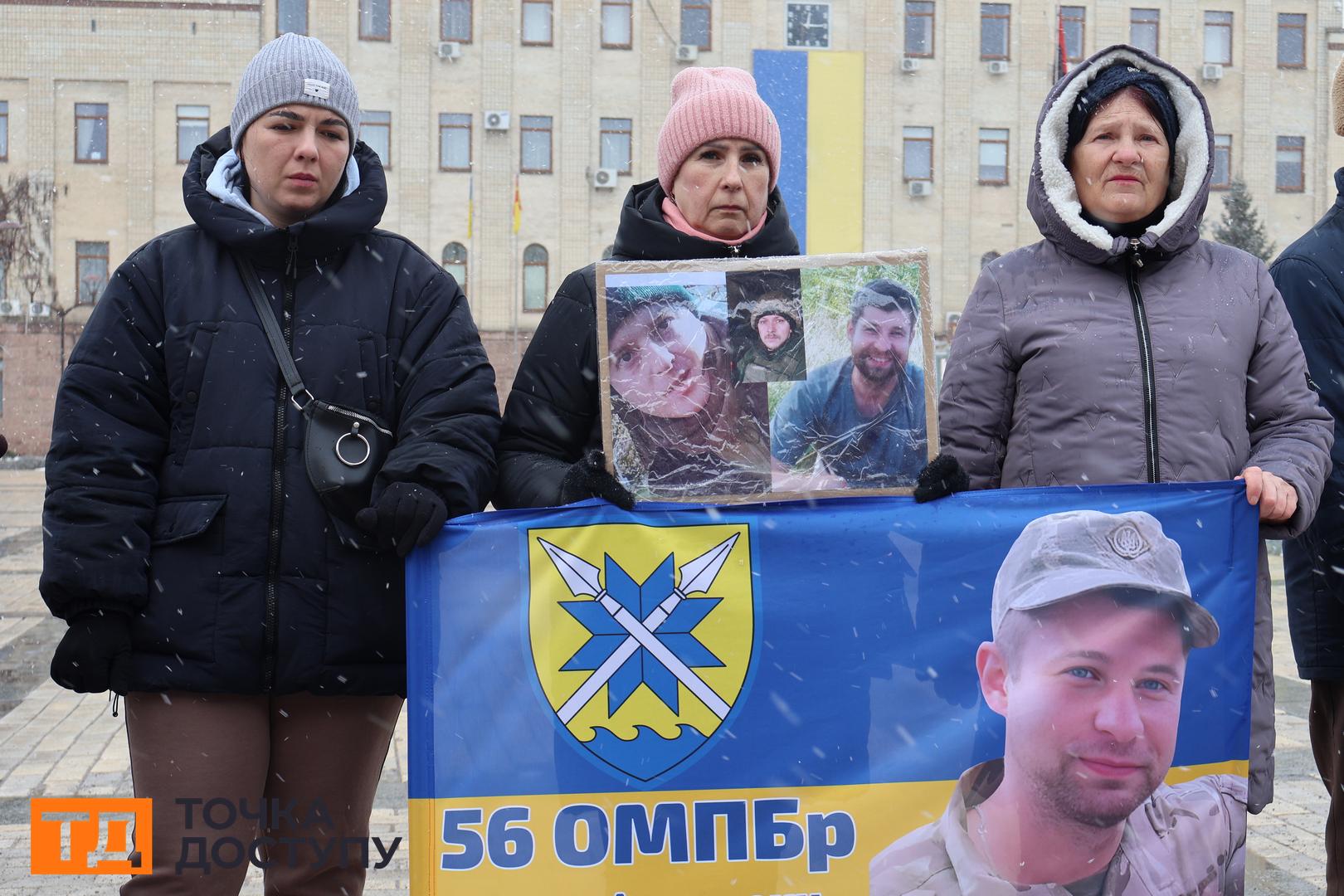 Жінка тримає плакат з портретом сина