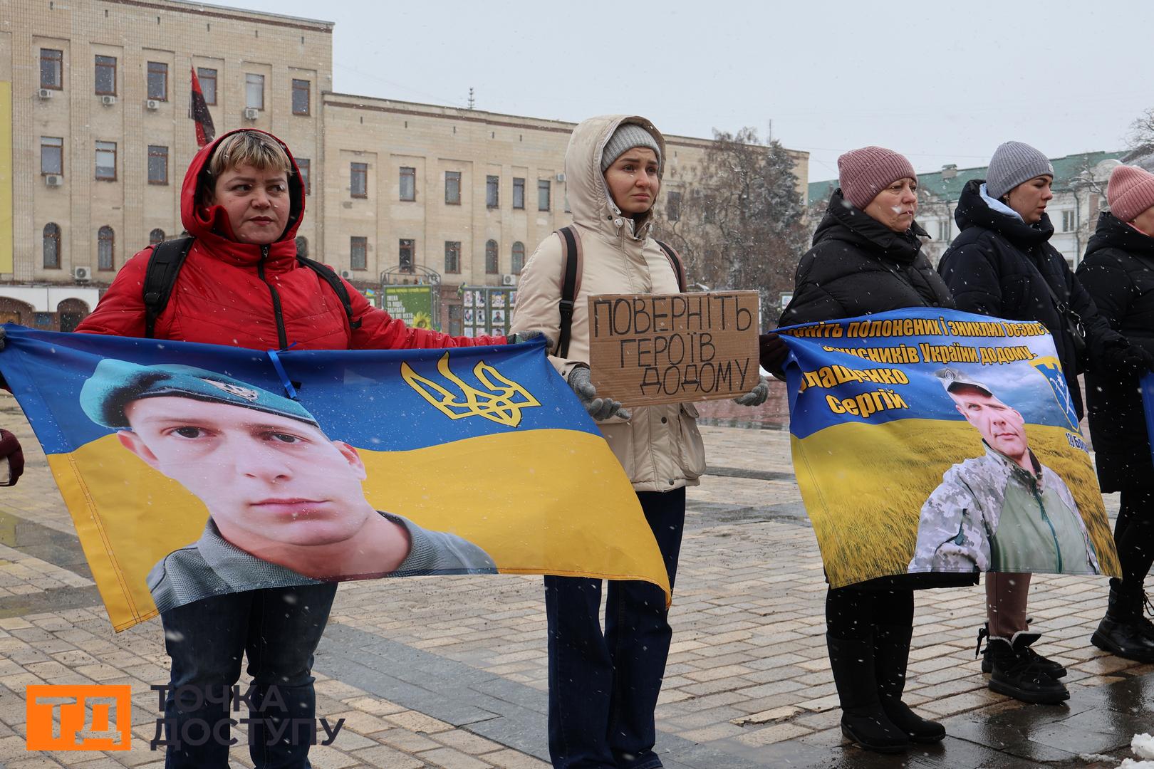 Жінка з плакатом в руках "Поверніть героїв додому"