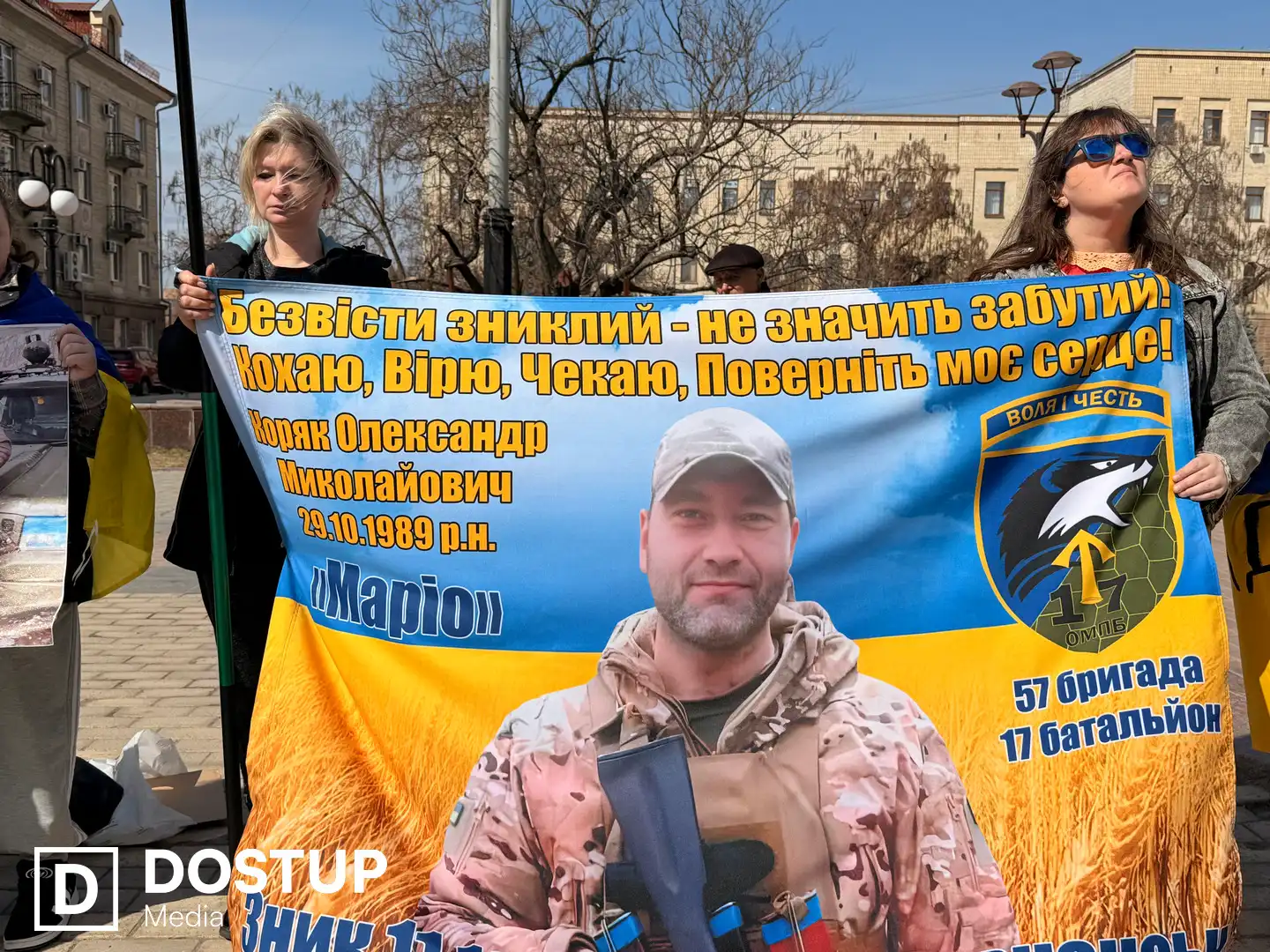 Дружина тримає плакат із портретом чоловіка-військового