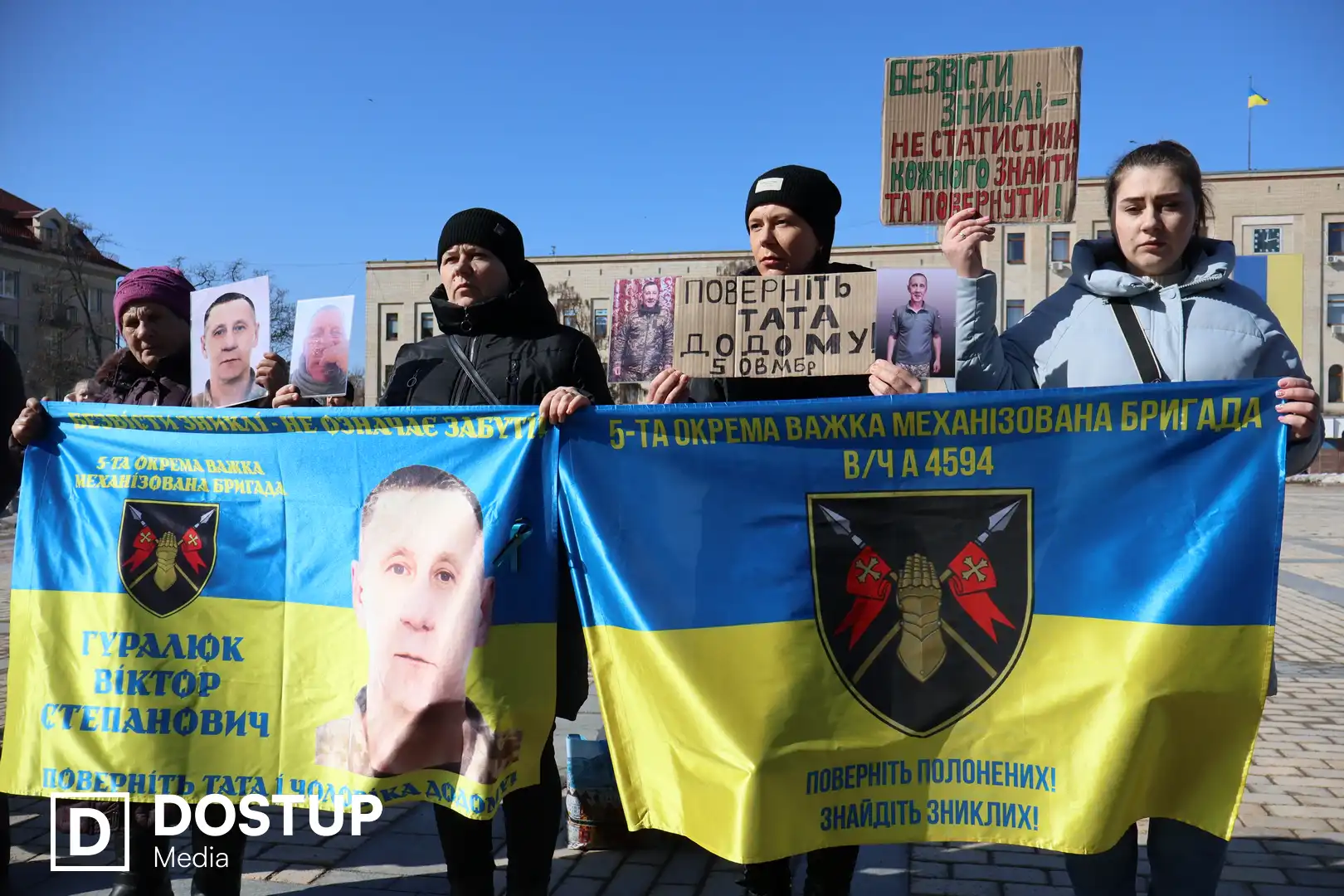 Рідні тримають в руках плакати з портретами військових